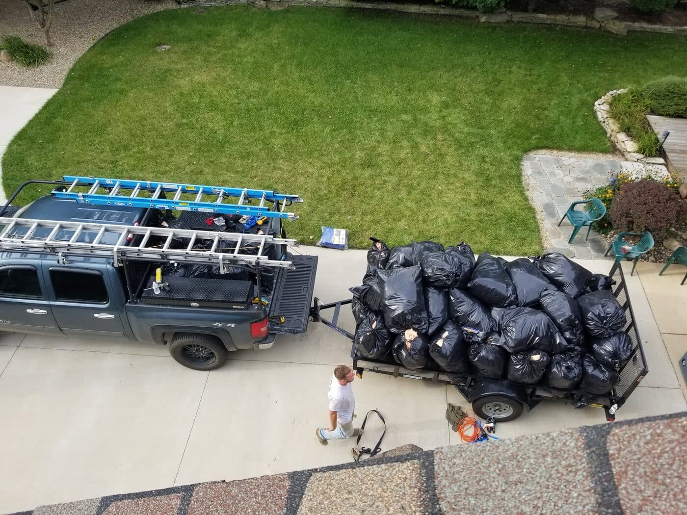 A truck and trailer stacked with bags of removed attic insulation